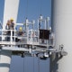 Workers on a hanging platform repair a damaged rotor blade on a
