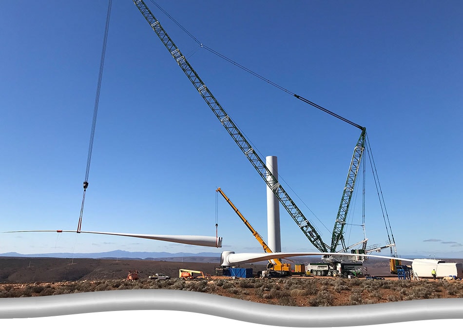 Crane Mobilization Optimization and Management. Green main crane working at angle, lifting up wind turbine blade with help from yellow supporting crane.