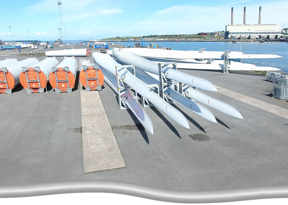 Onshore component of an offshore wind energy project. Supply of wind turbine blades and parts onshore, gathered and organized, ready for transport out to the water.