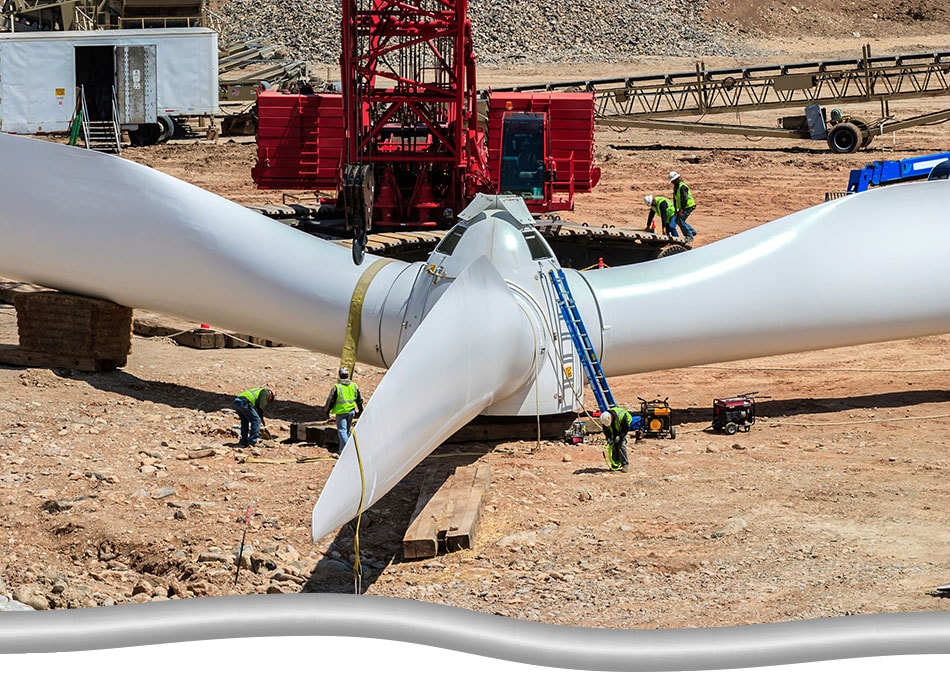 Technicians working on assembling wind turbine parts on the ground..